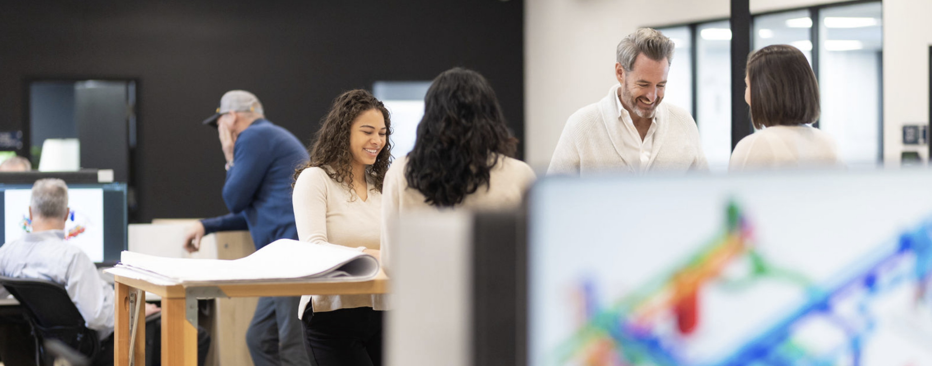 CDS team members working in the office, standing at a work table and smiling