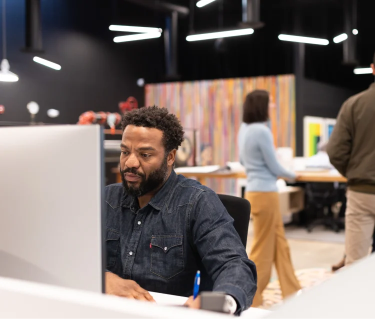 CDS team member working at his desk, writing while looking at the computer